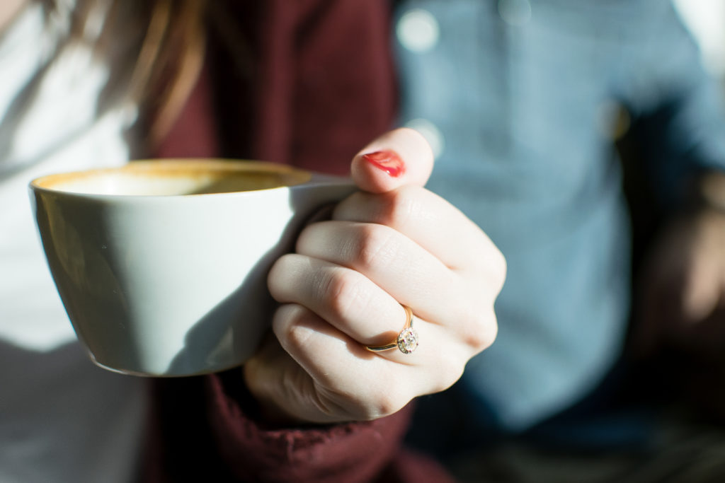 Engagement ring shot with a coffee mug