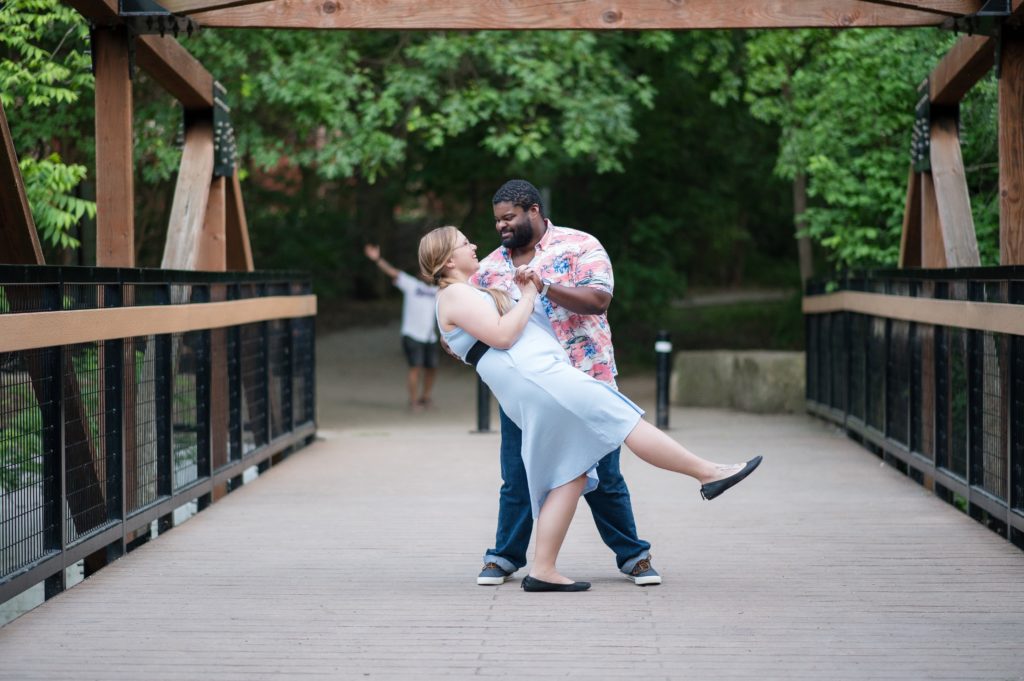 photobomber appears in the background of an engagement session dip shot at prairie creek park