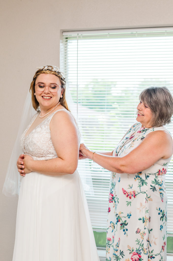 Bride's mother helps her into her dress before her Dallas Arboretum wedding. 