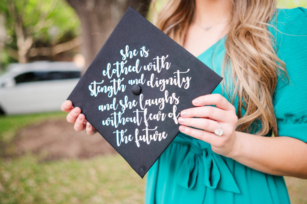 Graduation cap with text reading "she is clothed with strength and dignity and she laughs without fear of the future" during a senior session at Flippen Park