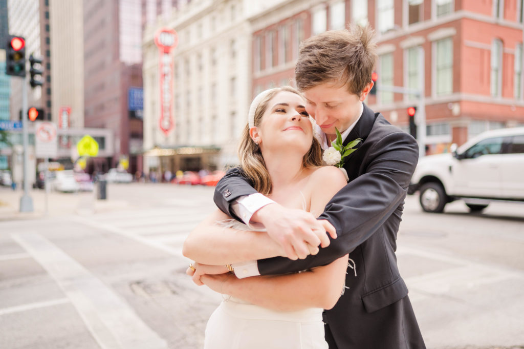 Bride and Groom embrace on a street corner for their downtown dallas wedding by the Majestic Theater