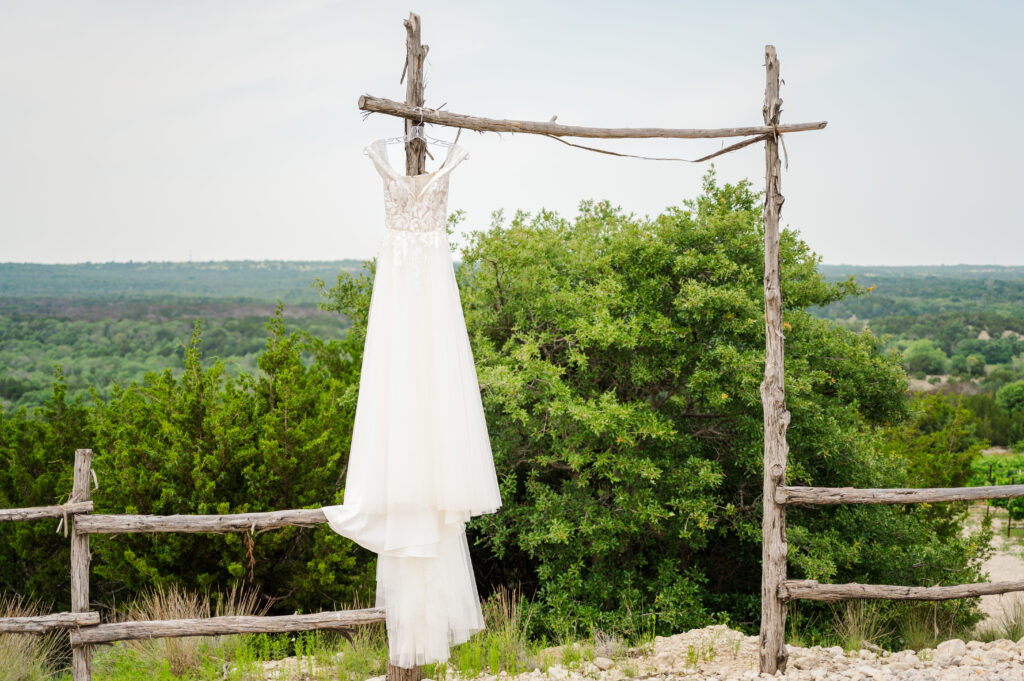 Wedding dress hanging from a gate post in a Texas vineyard 