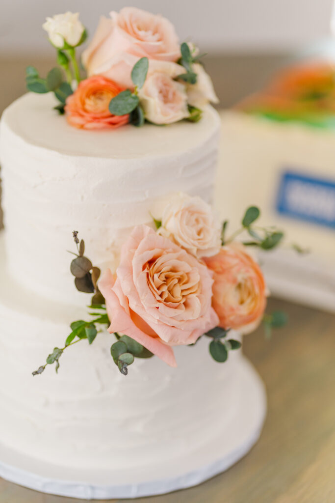 Pink and peach colored florals on a small white wedding cake