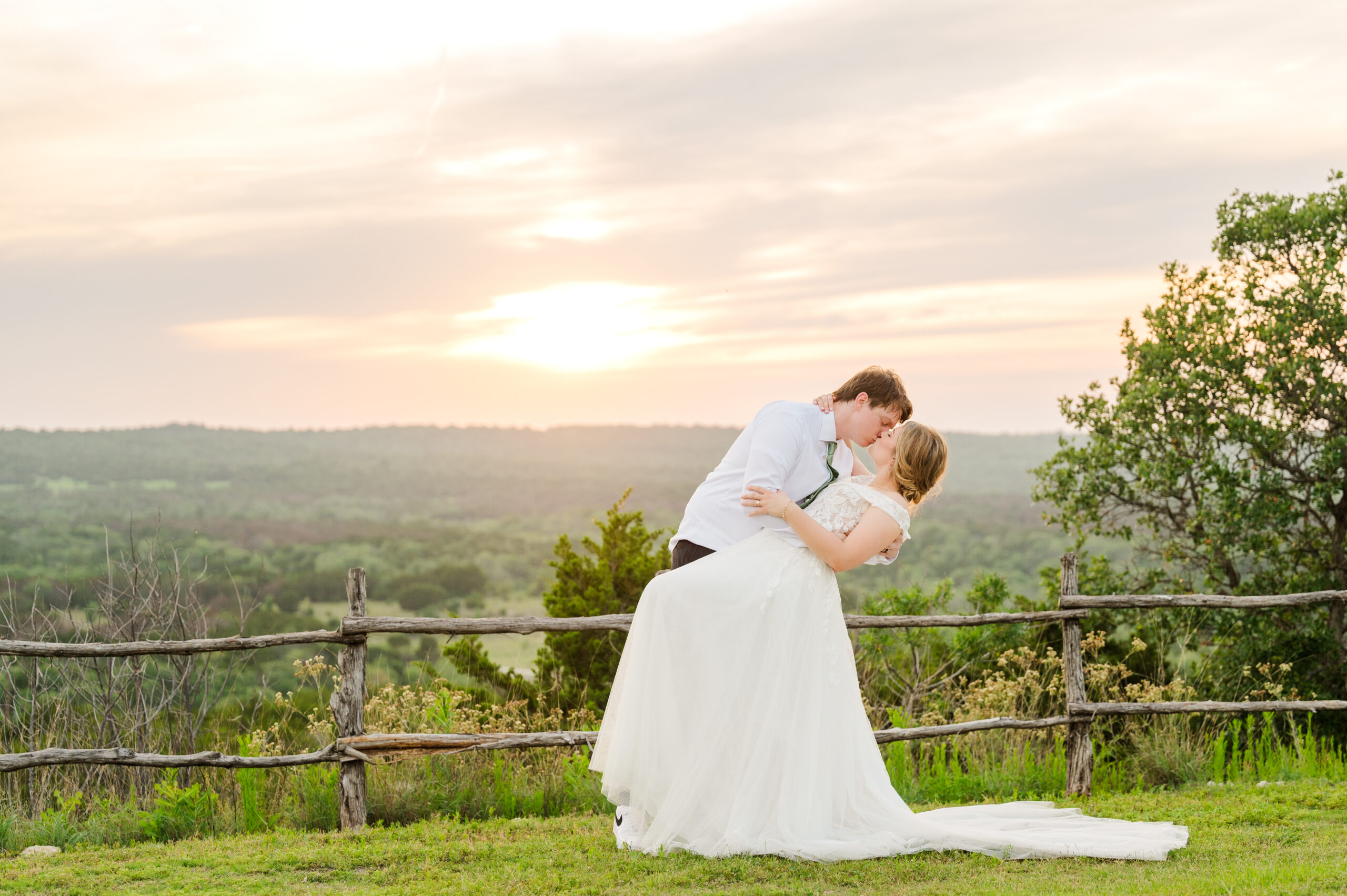 Couple shares a dip kiss at a Texas vineyard wedding with a sunset in the background